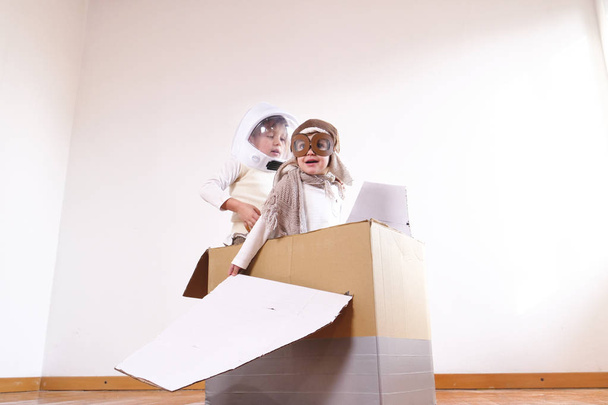 happy adorable children dressed as pilots playing in handmade cardboard box plane  - Photo, Image