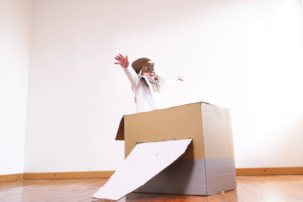 happy adorable little girl dressed as pilot playing in handmade cardboard box plane  - Valokuva, kuva