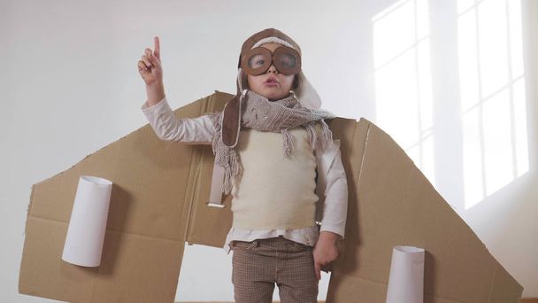 playful little boy dressed as aviator pilot in handmade cardboard box plane  - Photo, Image