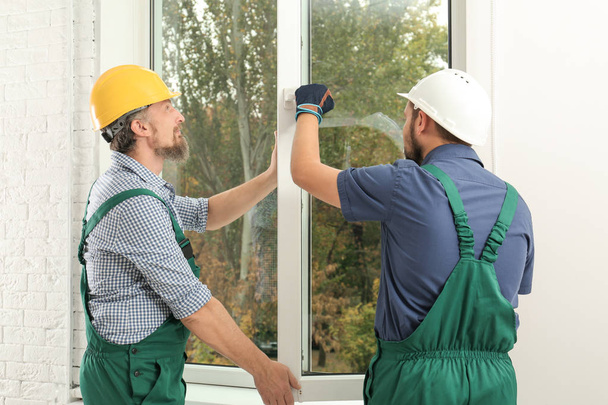 Construction workers installing new window in house - 写真・画像