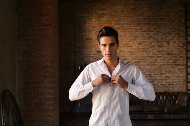 handsome brunette Caucasian man dressing on white shirt  - Fotografie, Obrázek