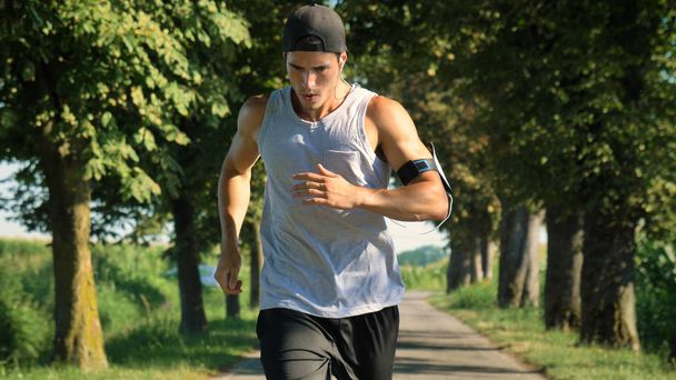 atleta hombre corriendo al aire libre con brazalete de teléfono en la mano
 - Foto, Imagen