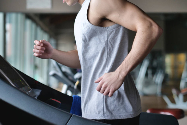 partial view of muscular man running on treadmill in gym  - Foto, afbeelding