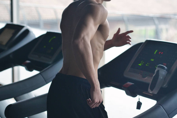 spor salonunda koşu bandı üzerinde çalışan gömleksiz kaslı adamın resim kırpılmış  - Fotoğraf, Görsel