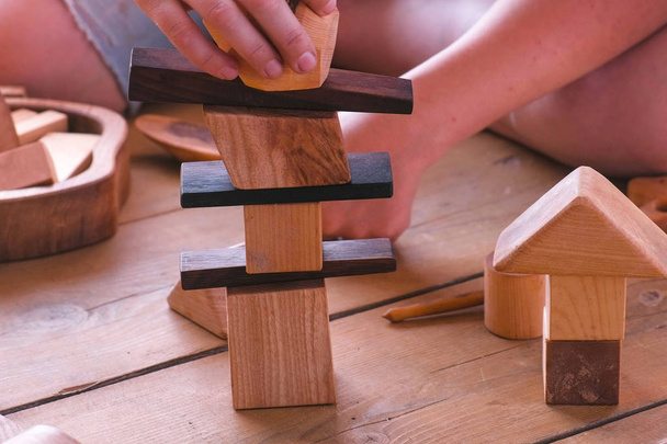 Woman is building a tower from wooden blocks. Close-up hands. - Фото, зображення
