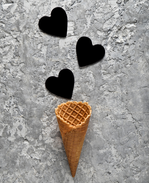 Chifre de waffle vazio e corações pretos em um fundo de concreto cinza, tendência minimalista, top vie
 - Foto, Imagem