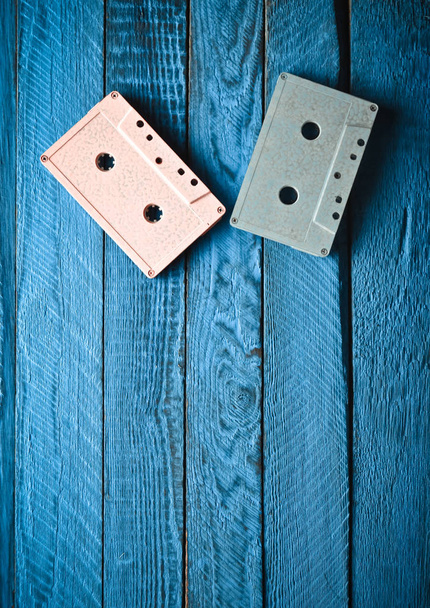 zweifarbige Pastell-Audiokassette auf blauem Holzhintergrund. Draufsicht, minimalistischer Tren - Foto, Bild