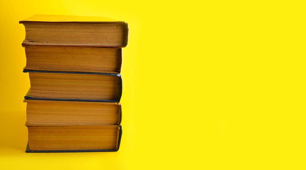 Copy space, stack of old books on a yellow background - Foto, afbeelding