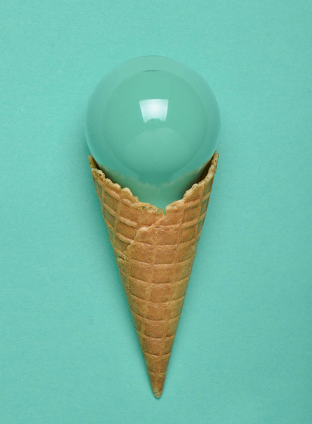 Creative, conceptual layout, painted incandescent bulb in a waffle horn on a mint pastel background, top view, minimalist tren - Valokuva, kuva