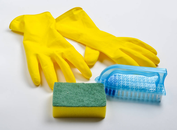 Equipement de nettoyage sur fond blanc. Gants en latex jaune, brosse, éponge
. - Photo, image