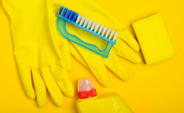 Equipo de limpieza sobre fondo amarillo. Guantes de látex, cepillo, esponja, botella de limpiador, vista superior, estilete plano
 - Foto, Imagen