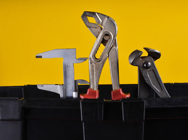 Garage Kunststoff-Werkzeugkasten mit Arbeitswerkzeugen isoliert auf einem gelben. Zangen, Schraubenschlüssel, Bremssattel - Foto, Bild