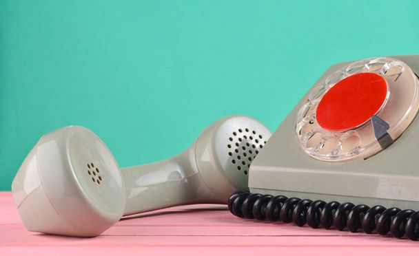 Роторный ретро-телефон на столе у мятной зеленой стены
 - Фото, изображение