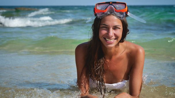 Beautiful young woman smiles at the sea, happy in a swimsuit wearing a diving mask. - Fotografie, Obrázek