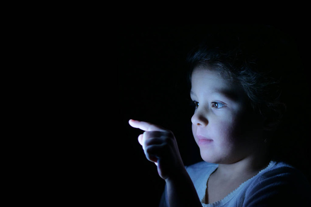 A little girl with her finger presses in front of her and bright futuristic graphics appear. Concept of: future, network, technology, security for children. - Φωτογραφία, εικόνα