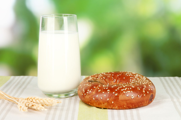 Bread roll and glass of milk on nature background - Foto, afbeelding