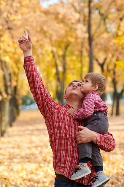 Père et fils jouent et s'amusent dans le parc de la ville d'automne. Ils posent, sourient, jouent. Arbres jaune vif
. - Photo, image