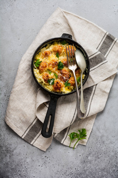 Meatballs with cheese and cream sauce in cast iron pan on gray vintage background. Top view. - Фото, зображення