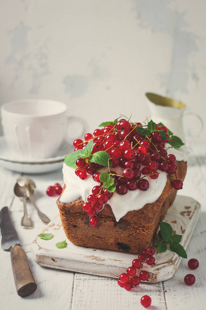 Bundt cake with glaze and red currant on white wooden vintage background. Toned image. Top view. - Valokuva, kuva