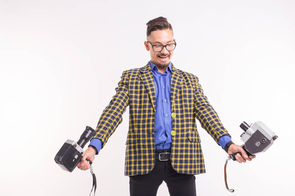 Technologien, Fotografie und Personenkonzept - Porträt eines lustigen jungen brünetten Mannes, der ein Selfie mit zwei Kameras auf weißem Hintergrund macht - Foto, Bild