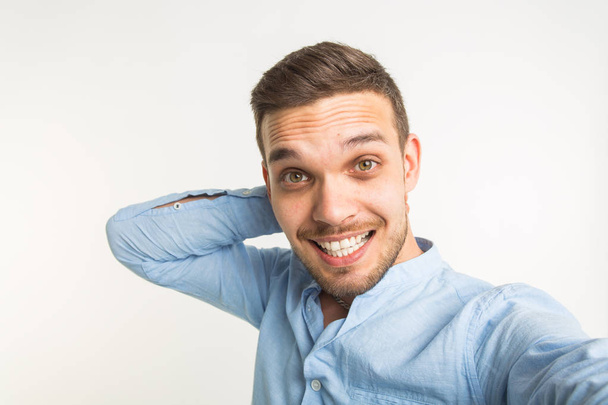 Close up portrait of a cheerful bearded man taking selfie over white background - Photo, Image