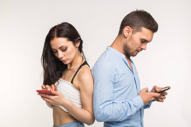 Smartphone dipendenza concetto - Sconvolto coppia in piedi l'uno all'altro su sfondo bianco
 - Foto, immagini