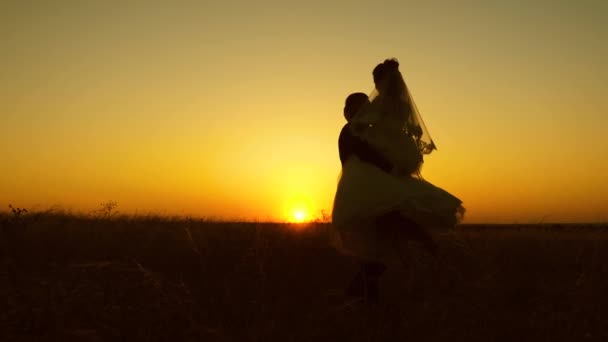 Mladá nevěsta a ženich krouží na pozadí romantické rudý západ slunce. Líbánky. Vztah mezi mužem a ženou - Záběry, video