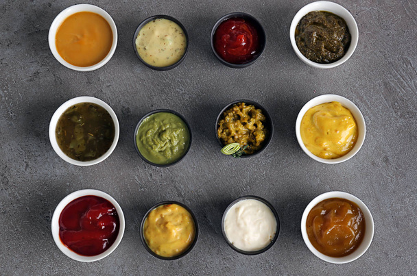 Diferentes salsas sabrosas en cuencos sobre mesa gris
 - Foto, imagen