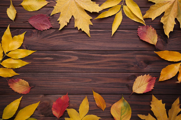 Red and Orange autumn leaves on brown wooden background - Fotó, kép