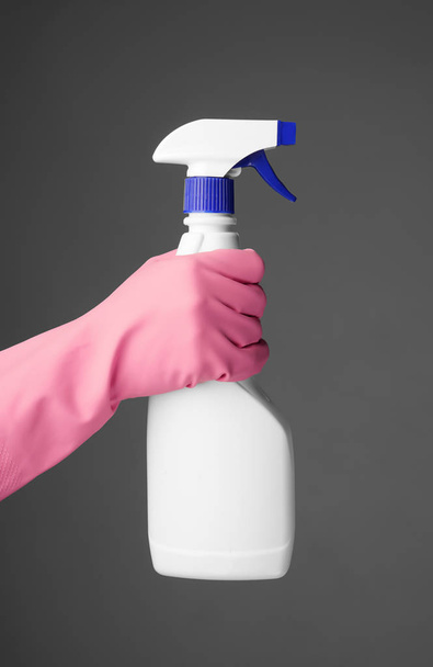 Donna in possesso di bottiglia spray di detergente su sfondo grigio
 - Foto, immagini