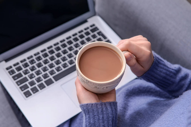 Женщина пьет ароматный кофе во время использования ноутбука, крупным планом
 - Фото, изображение