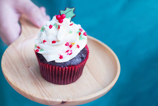 Close up cupcake with christmas tree shape serving on wooden plate at bakery shop. Christmas and new year holidays background concept. - Фото, изображение