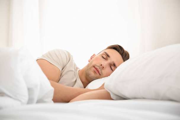 Красивый мужчина спит в постели дома
 - Фото, изображение