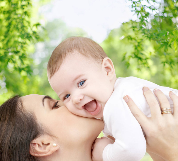 Mutter küsst Baby über grünen natürlichen Hintergrund - Foto, Bild
