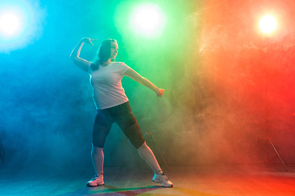 La danse moderne, le sport et les gens concept - jeune femme dansant jazz funk dans l'obscurité sous une lumière colorée
 - Photo, image
