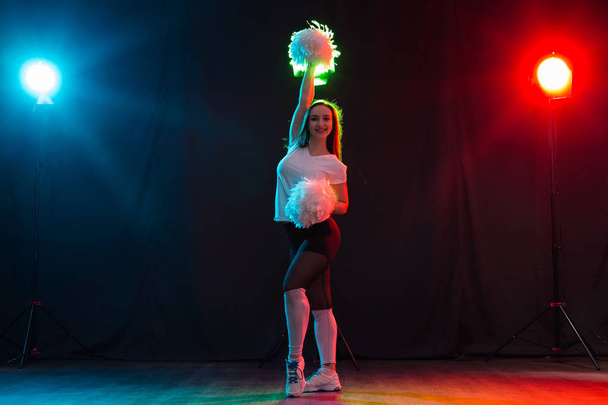 Девушка из группы поддержки танцует с помпонами на цветном фоне
 - Фото, изображение
