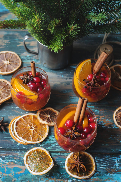 Traditional Christmas beverages with berries, lemon, cinnamon sticks and fir branches - Fotó, kép