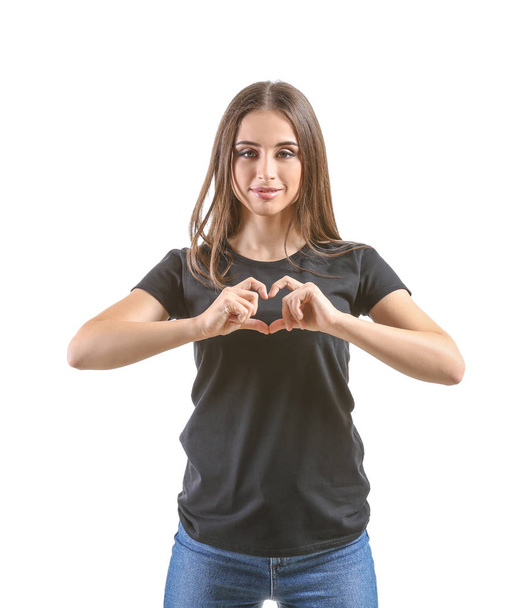 Young woman in stylish t-shirt making heart with her hands on white background - Zdjęcie, obraz