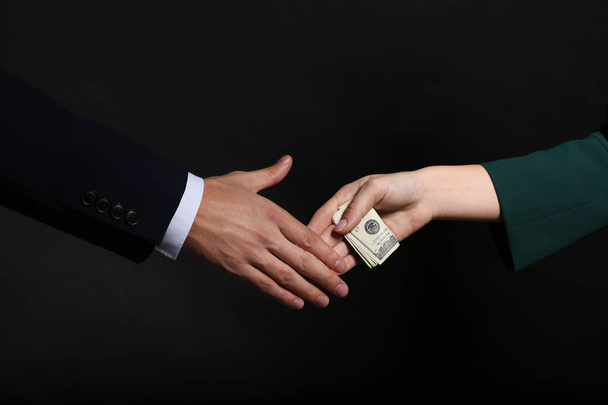 Geschäftsmann nimmt Bestechungsgeld von Frau mit dunklem Hintergrund an. Korruptionskonzept - Foto, Bild