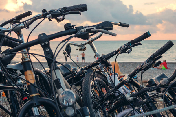 στάθμευσης, σειρά ποδηλάτων στην παραλία με συννεφιασμένο ουρανό φόντο ποδηλάτων - Φωτογραφία, εικόνα