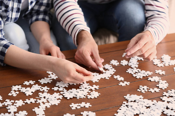 Young couple doing jigsaw puzzle at home, closeup - Foto, Imagem