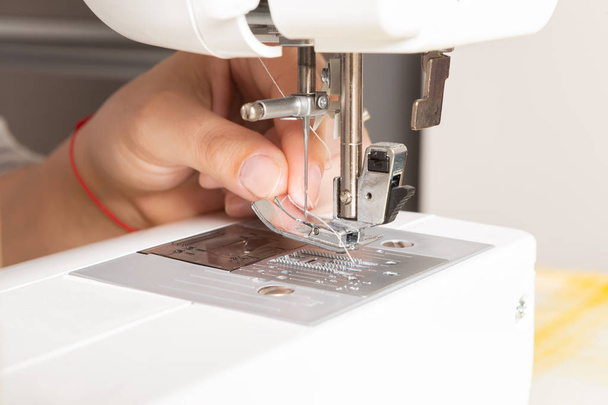 Máquina de coser que está siendo preparado por alguien para la sastrería mediante la colocación de hilo
 - Foto, imagen