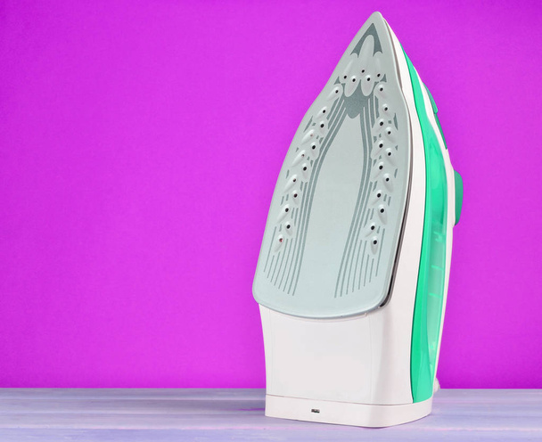 Iron for ironing on a colored pastel background, minimalist tren - Foto, afbeelding