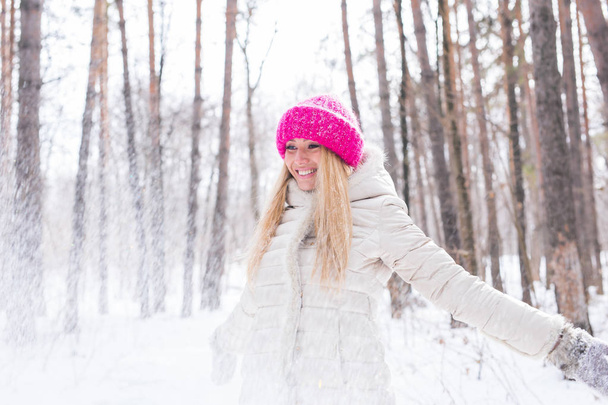 Happy young woman plays with a snow at snowy forest outdoor - Фото, изображение