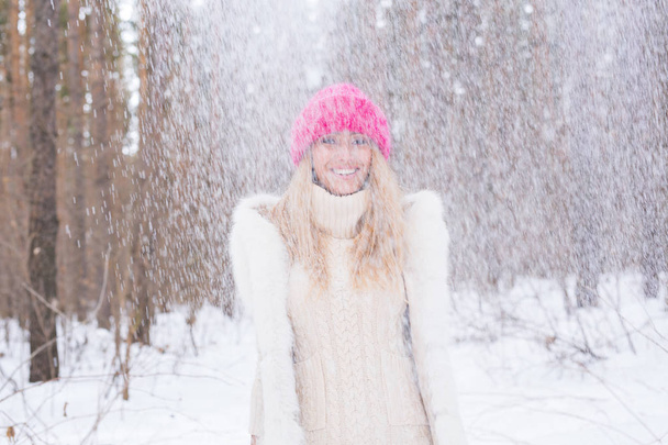 Diversión, invierno y concepto de la gente - Mujer joven atractiva vestida con abrigo lanzando nieve
. - Foto, imagen