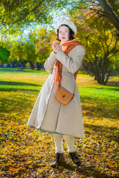 Woman in a light coat and beret in the autumn day on a walk in the park during - Photo, image