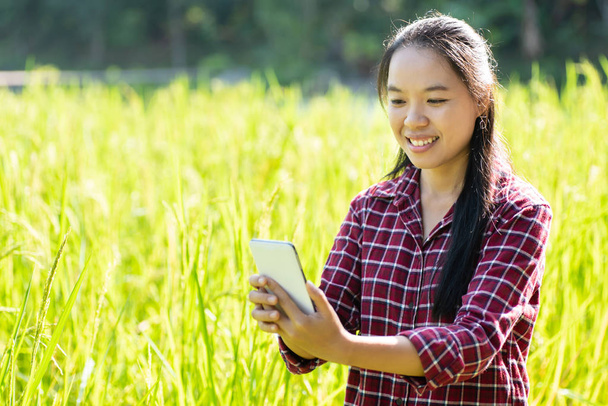 Ασιατικές γυναίκα (smart γεωργός) χρησιμοποιώντας έξυπνο τηλέφωνο για τη διαχείριση στον τομέα της βιολογικής ρύζι - Φωτογραφία, εικόνα