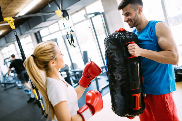 Portrait of beautiful woman wearing boxing gloves in gym - Foto, Imagen