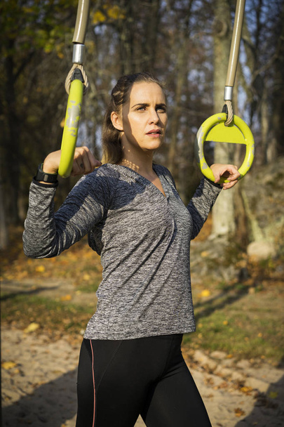 Молодая женщина в спортивной форме тренируется в спортзале на открытом воздухе
    - Фото, изображение
