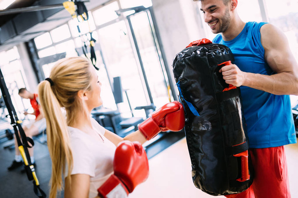 Portrait of beautiful woman wearing boxing gloves and her trainer - Φωτογραφία, εικόνα